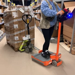 Mitarbeiterin steht auf dem 360Mover und zieht Palette mit Handhubwagen.